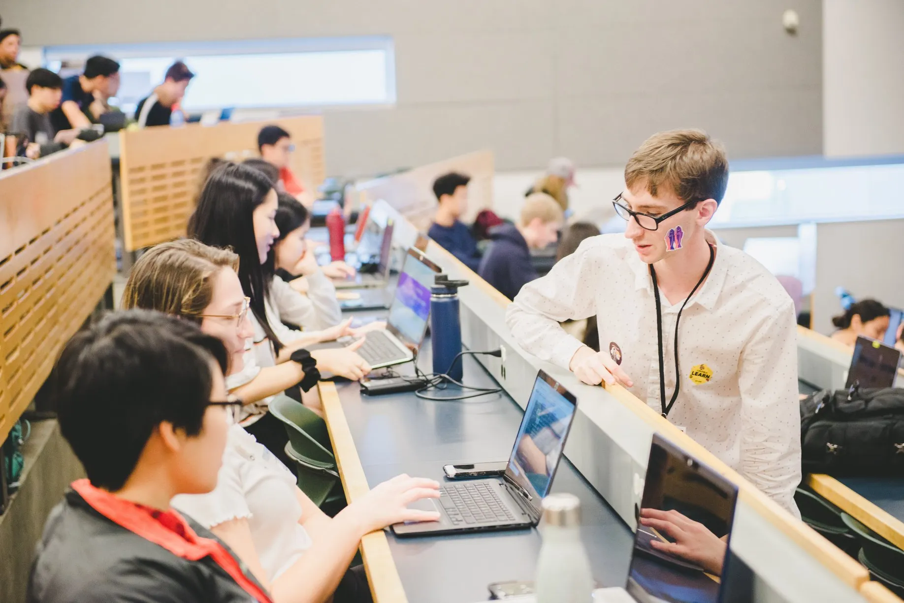 Giulio helping students with their laptops in a UBC lecture hall during a hackathon